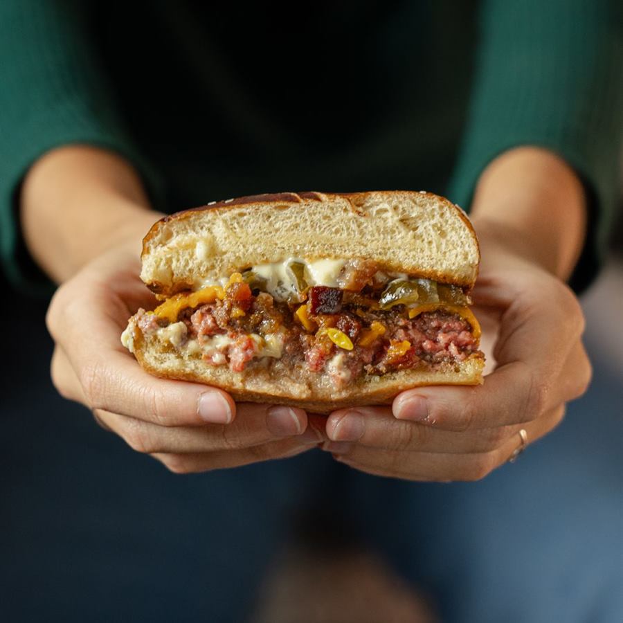 Burger cortado segurado nas mãos